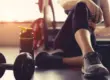 Dumbbell and water bottle on a gym floor, with a woman resting in warm, hazy sunlight after her workout with Healthwise Protein Shakes in Glendale, AZ.