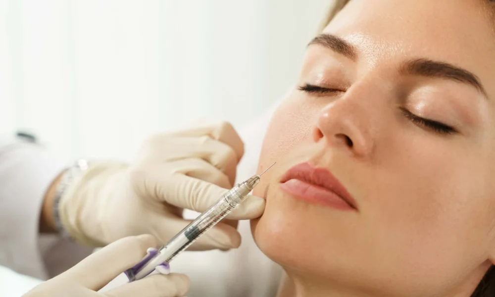 A woman receives a cosmetic injection in her cheek at Medical Spa in Glendale AZ Vida Bella Med Spa. The close up shows a professional wearing gloves administering the treatment while the client relaxes with her eyes closed.